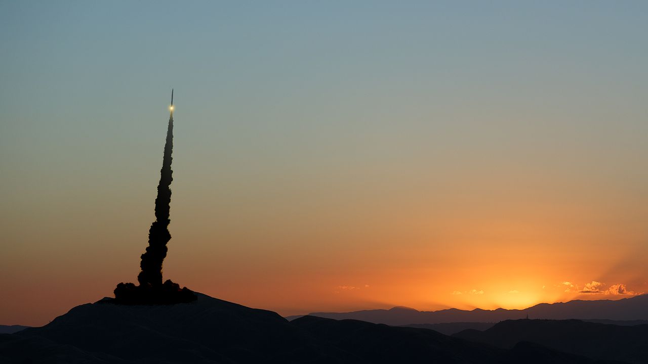 silhouetted image of rocket launching against a sunset background