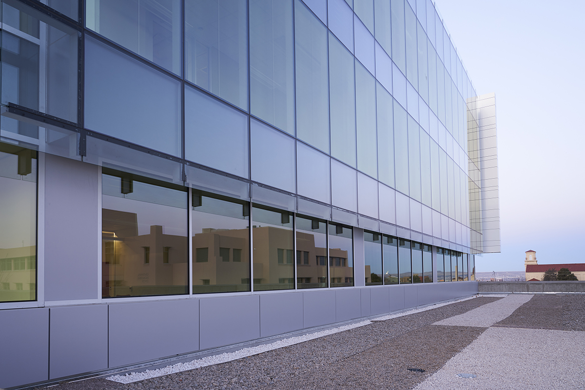 photo of the farris building reflecting the centennial engineering building in its walls of windows.