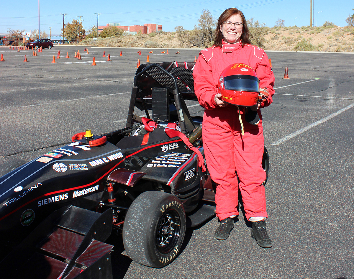 the university president, Garnett Stokes, stands beside an FSAE race car, which she has test driven