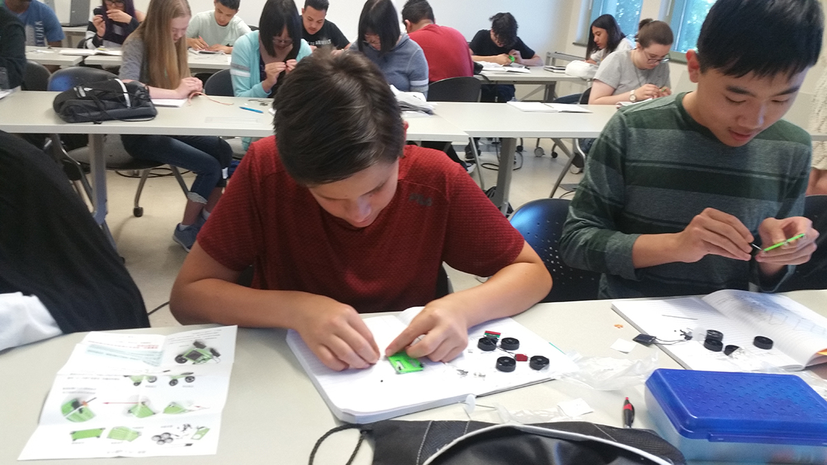 Photo of young students working in a classroom on engineering projects.